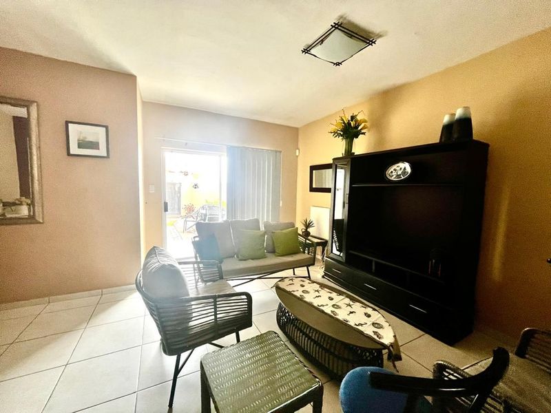 A living room featuring tiled flooring and a sliding glass door providing access to an outdoor area.