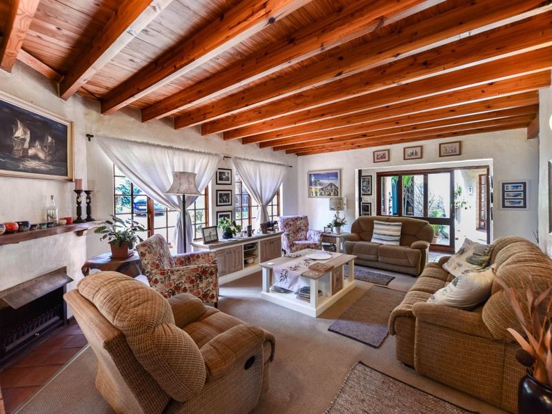 A cozy living room featuring exposed timber ceiling beams, a fireplace with a tiled hearth, and sliding glass doors leading to the exterior.
