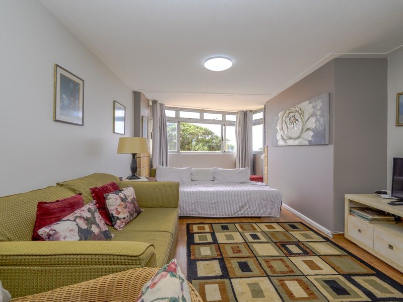 A well-lit bedroom featuring laminate flooring and a large window providing natural light.