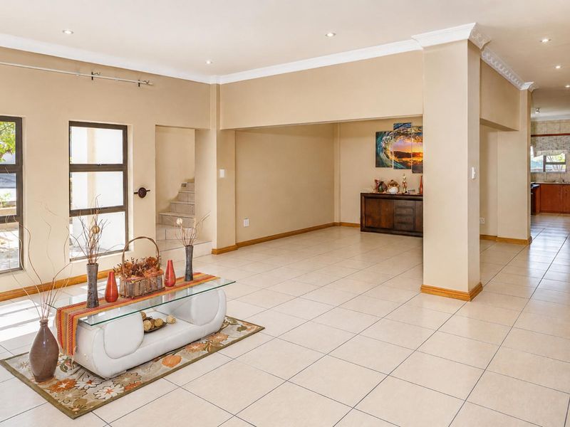 Spacious open-plan living area featuring neutral tiled flooring, recessed lighting, crown molding, and a view through to the kitchen area.