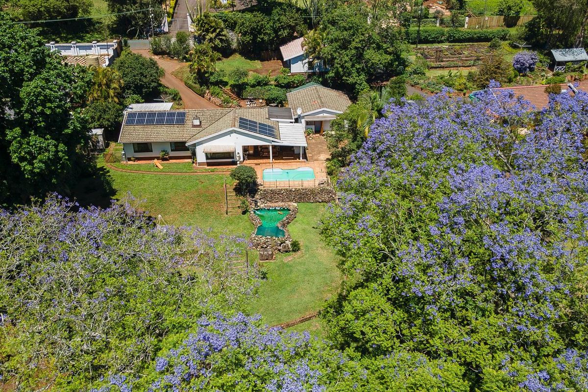 Aerial view of the property featuring a spacious garden, swimming pool, and solar panels installed on the roof.