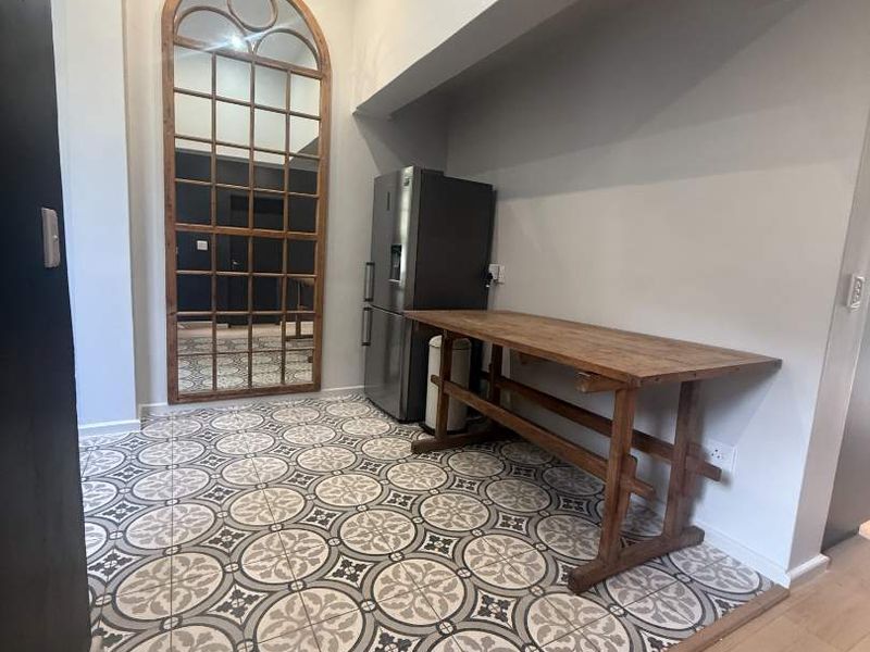 A modern kitchen area featuring decorative patterned floor tiles, recessed ceiling lighting, and a distinctive arched mirror feature.