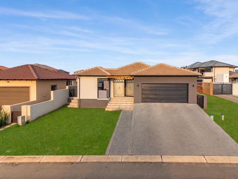 Modern single-story residential home featuring a tiled roof, paved driveway, double garage, and a well-maintained front lawn.