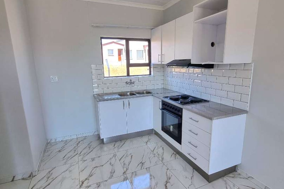 A modern kitchen featuring white cabinetry, marble-look tiled flooring, a built-in oven, hob, extractor fan, and a double sink with subway tile backsplash.