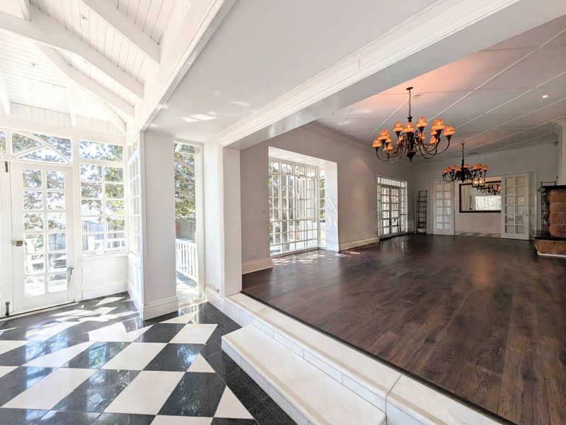 Spacious living area featuring vaulted ceilings, dark timber flooring, a stone fireplace, and elegant french doors leading to outdoor spaces.