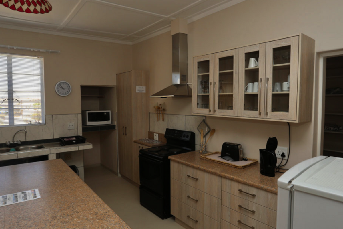A functional kitchen featuring light wood-grain cabinetry, granite-look countertops, a stainless steel extractor fan, and a dedicated built-in microwave nook.