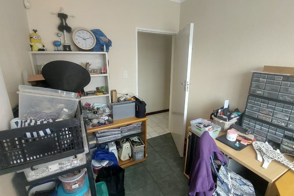 A functional bedroom or utility space featuring tiled flooring and a standard interior door, currently utilized as a workspace.