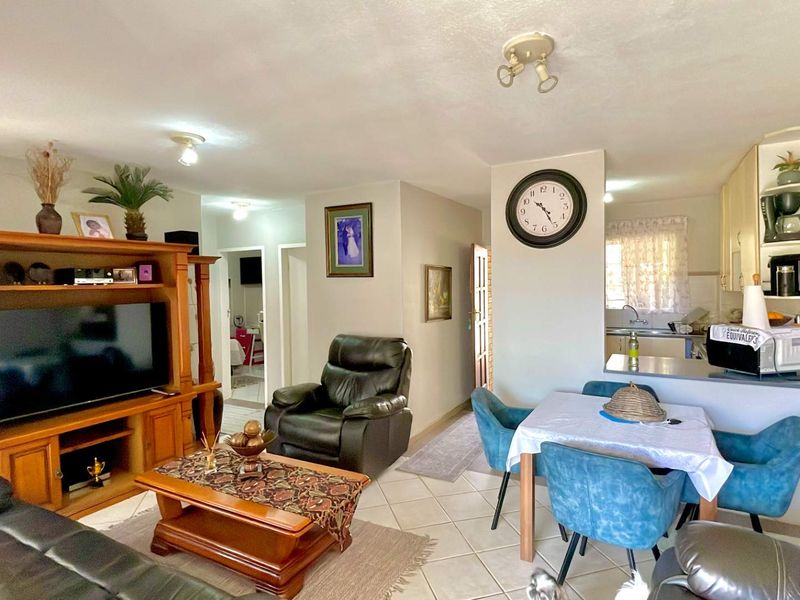 Open plan living and dining area featuring tiled flooring and a functional kitchen with built-in cabinetry and a breakfast counter.