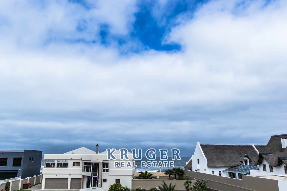 An elevated view of the property exterior, showcasing the architectural design, roof structure, and proximity to the coastline.