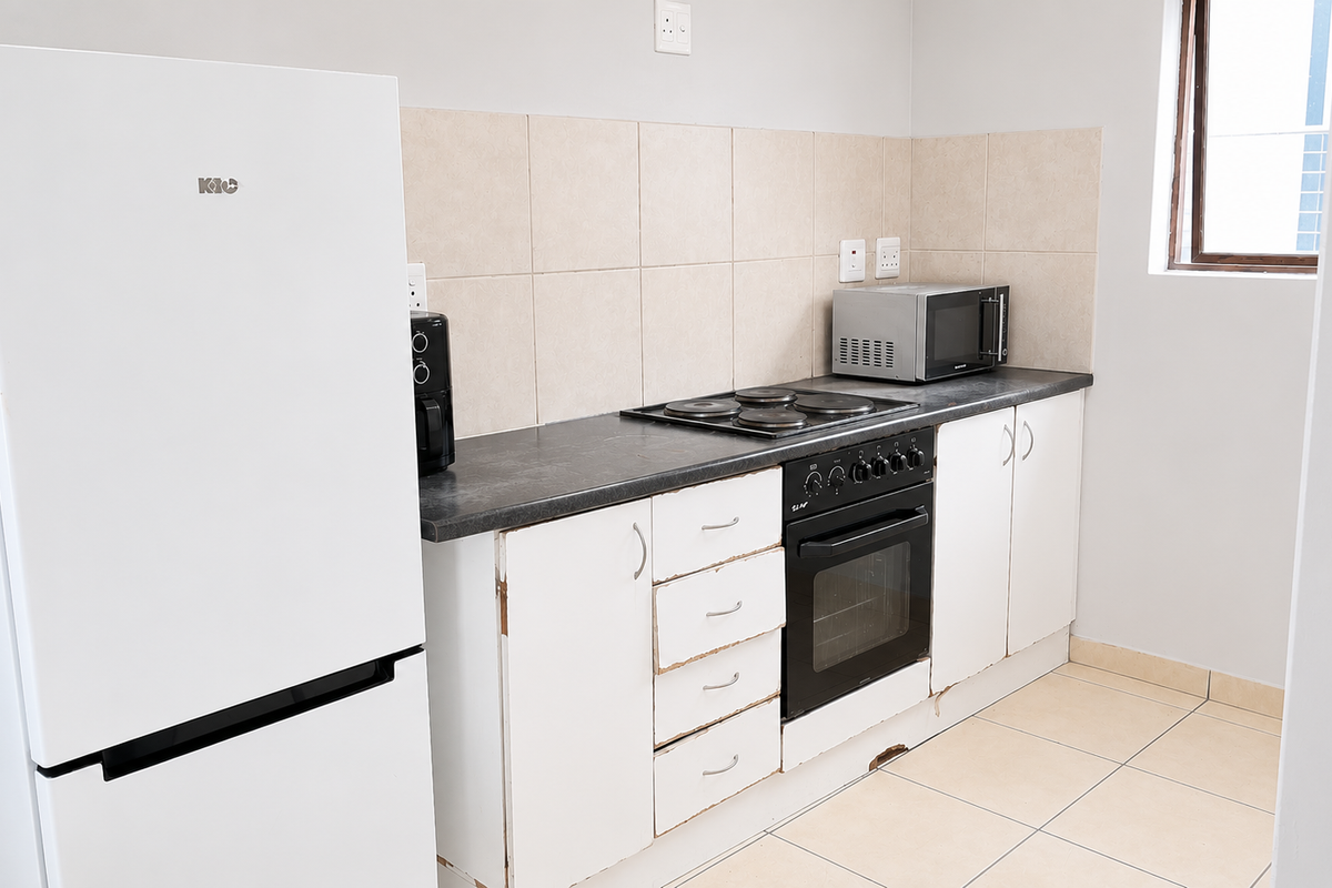 A functional kitchen featuring built-in cabinetry, an electric oven and hob, tiled splashbacks, and tiled flooring.
