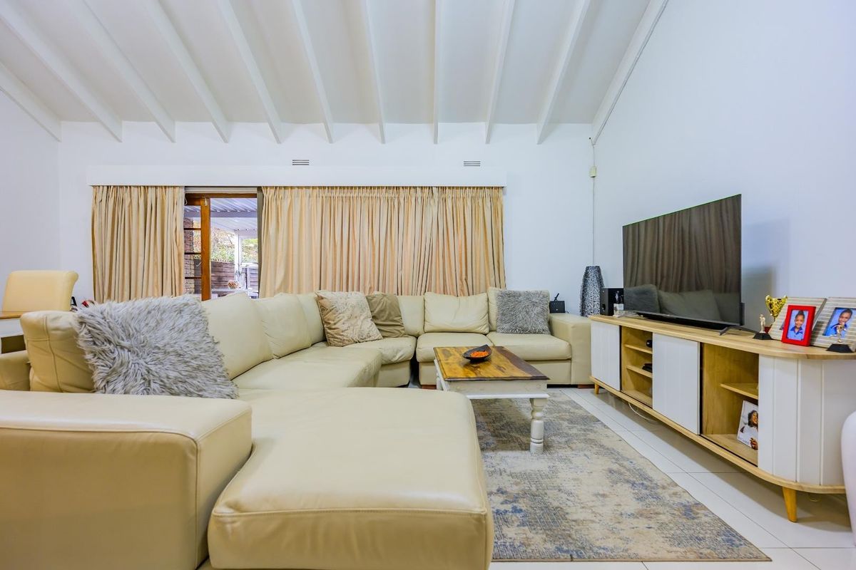 Spacious living room featuring a high vaulted ceiling with exposed rafters, tiled flooring, and direct access to an outdoor patio area.