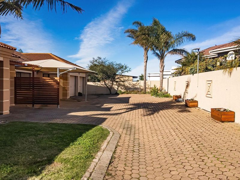 Spacious paved driveway and front courtyard area featuring a shade sail, boundary walls, and access to the garage.