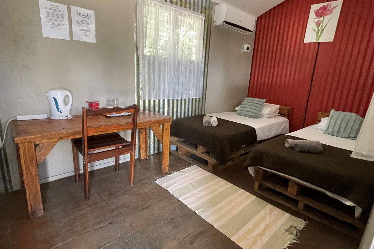 A rustic bedroom featuring corrugated metal wall accents, timber flooring, and a wall-mounted air conditioning unit.
