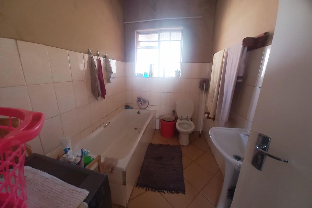 A functional bathroom featuring a bathtub, pedestal basin, and toilet, with tiled walls and unfinished upper wall surfaces.