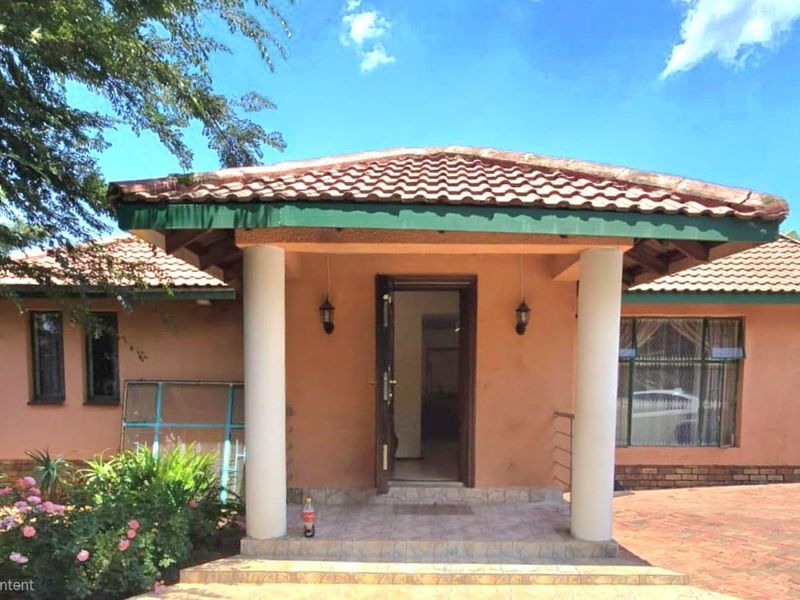 Front elevation of a single-story house featuring a covered entrance porch with concrete columns, tiled roof, and a paved driveway.