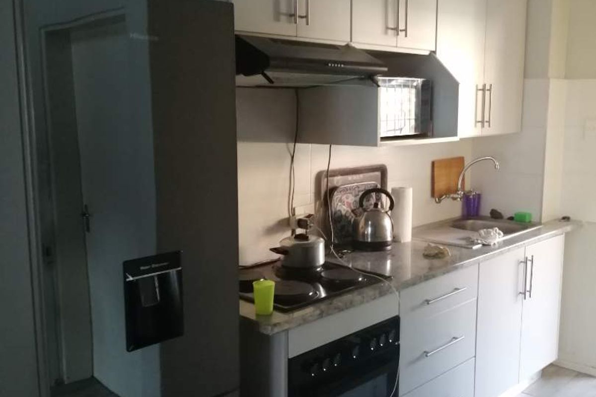 A functional kitchen featuring built-in cabinetry, laminate countertops, an electric oven with hob, and tiled flooring.