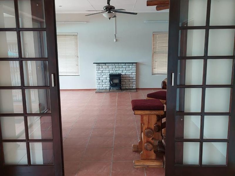 Spacious living area featuring tiled floors, a brick fireplace, and large sliding glass doors providing access to the room.
