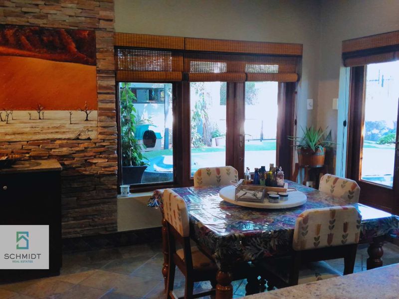 Dining area featuring a stone-clad feature wall, tiled flooring, and timber-framed glass doors providing direct access to the outdoor pool area.