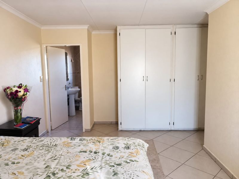 A bedroom featuring built-in cupboards, tiled flooring, and direct access to an en-suite bathroom.