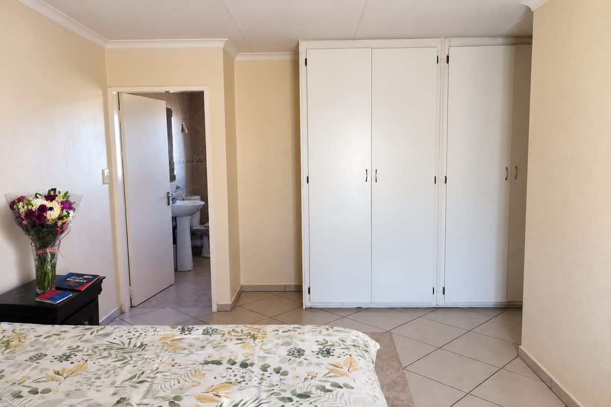 A bedroom featuring built-in cupboards, tiled flooring, and direct access to an en-suite bathroom.