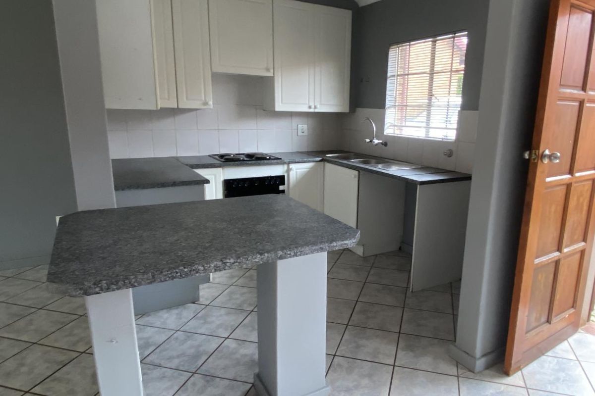 Functional kitchen featuring white cabinetry, dark laminate countertops, a built-in hob and oven, and a breakfast bar island.