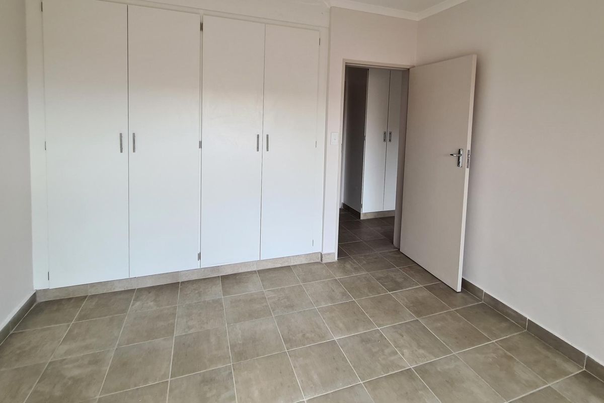 A clean, empty bedroom featuring neutral tiled flooring and ample built-in cupboard storage, providing a versatile space ready for personalization.