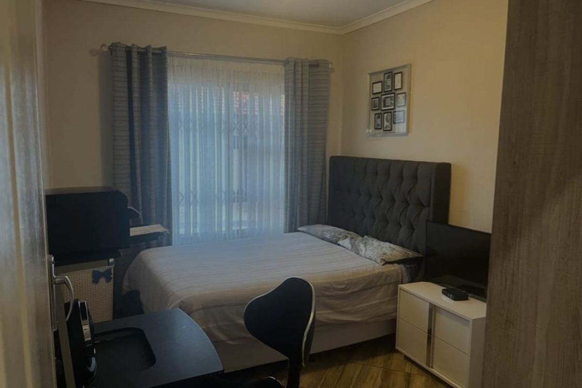 A cozy bedroom featuring tiled flooring and a window with curtain treatments, providing a functional and comfortable living space.
