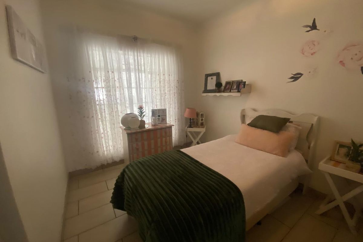 A cozy bedroom featuring tiled flooring and a window with sheer curtains, providing a neutral base for personalization.