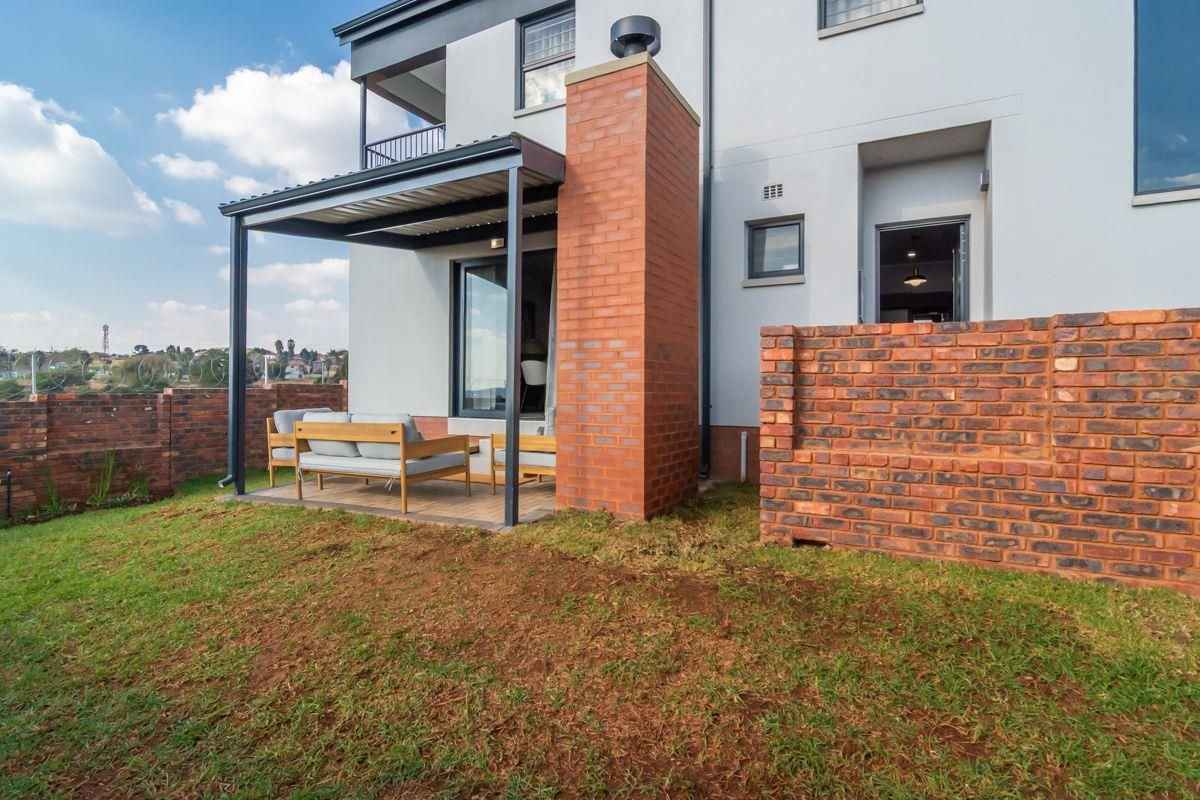 Rear view of the property featuring a covered patio, brick chimney, and a private garden area with boundary walling.