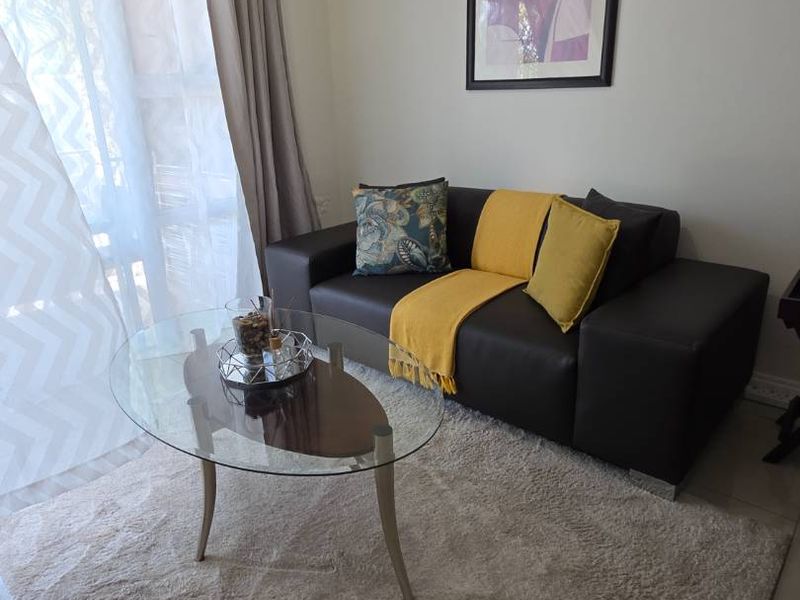 A cozy living room area featuring tiled flooring and a large sliding glass door that provides natural light.