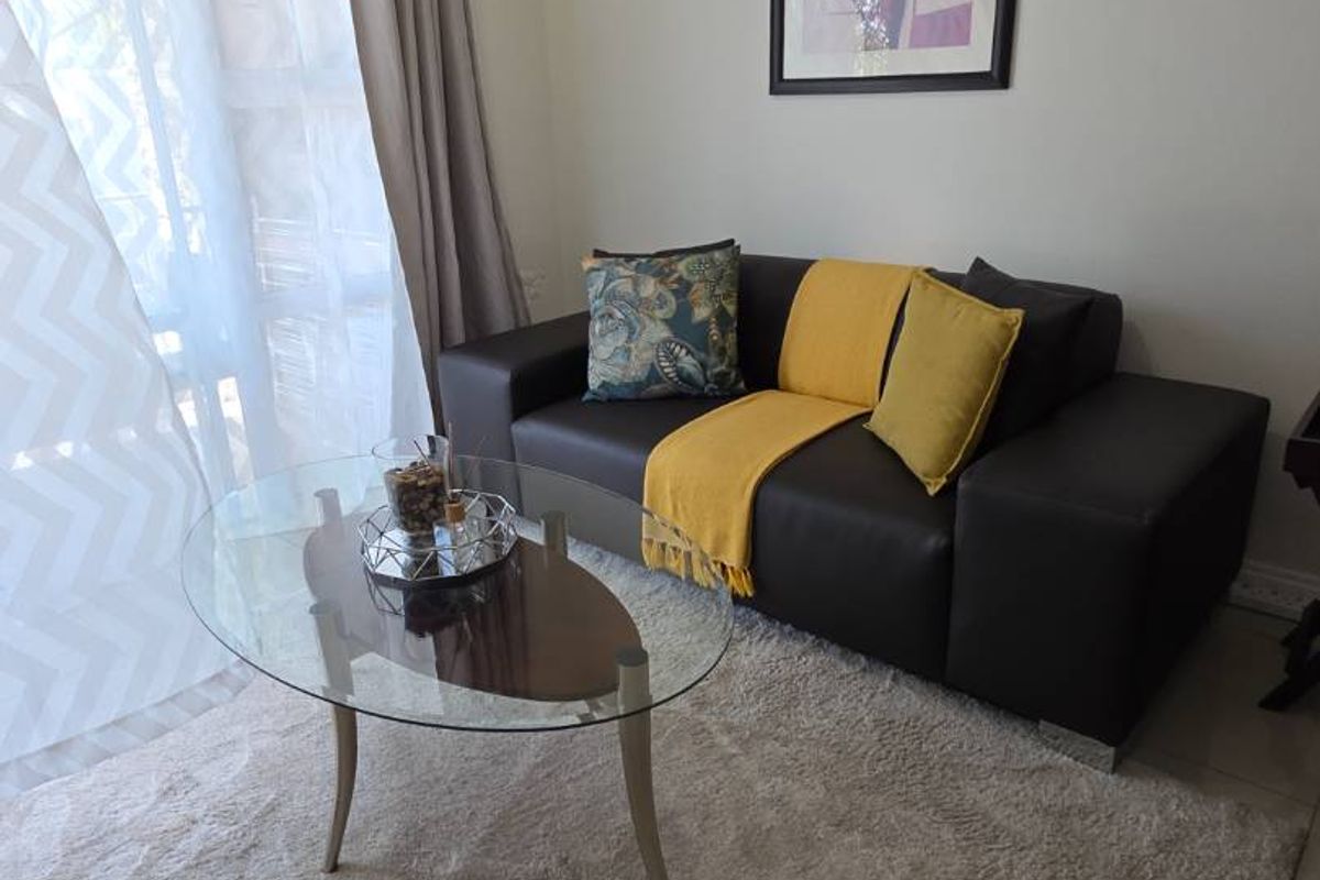 A cozy living room area featuring tiled flooring and a large sliding glass door that provides natural light.