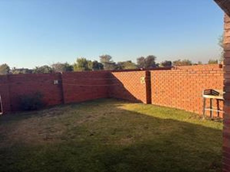 A private rear garden area featuring a lawn and enclosed by high brick boundary walls with a built-in braai facility.