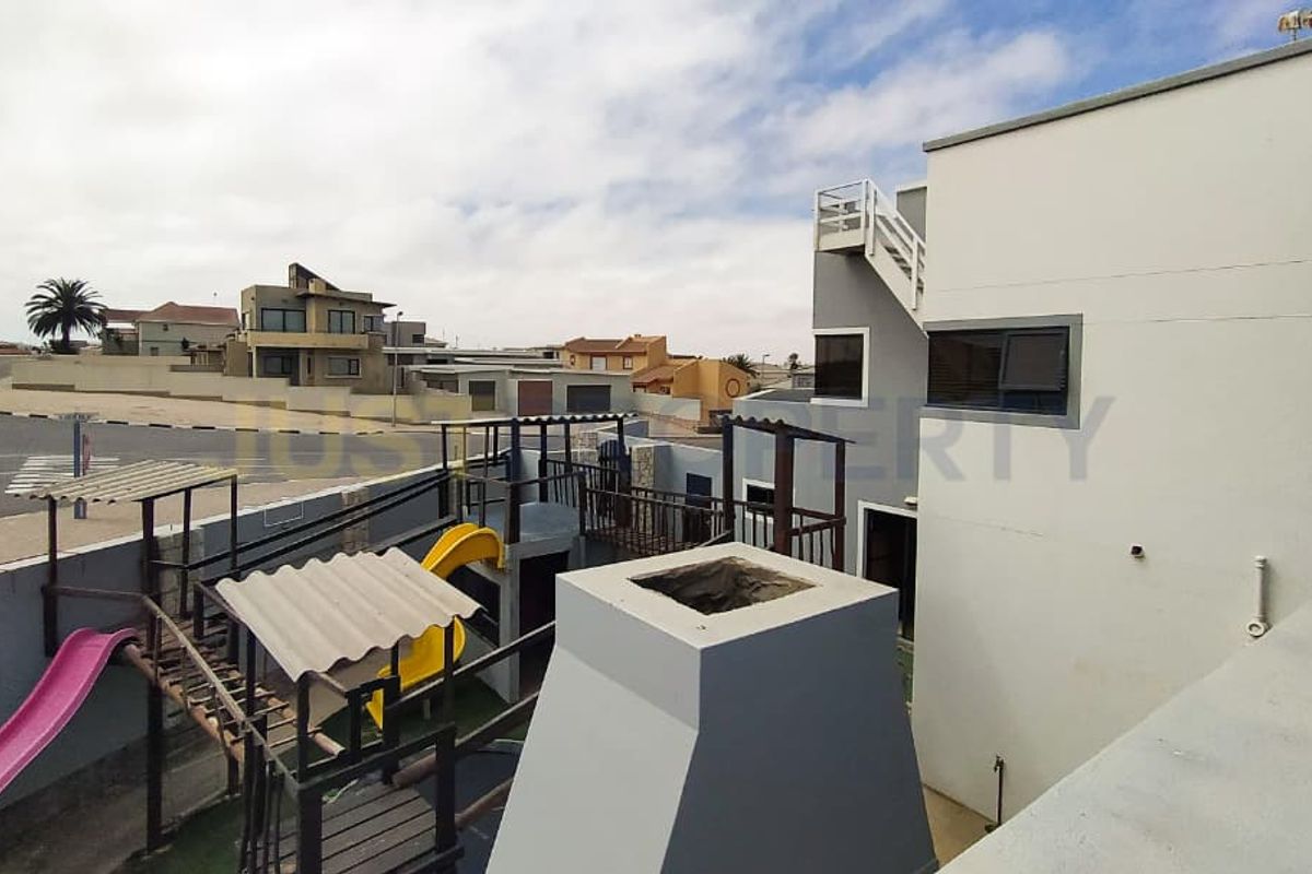 An elevated view of the rear exterior area featuring a built-in outdoor fireplace and a multi-level play structure.