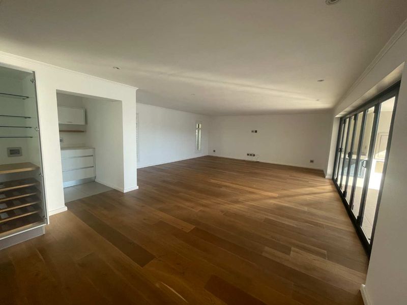Spacious open-plan living area featuring high-quality hardwood flooring, recessed lighting, and large bi-fold doors leading to the exterior.