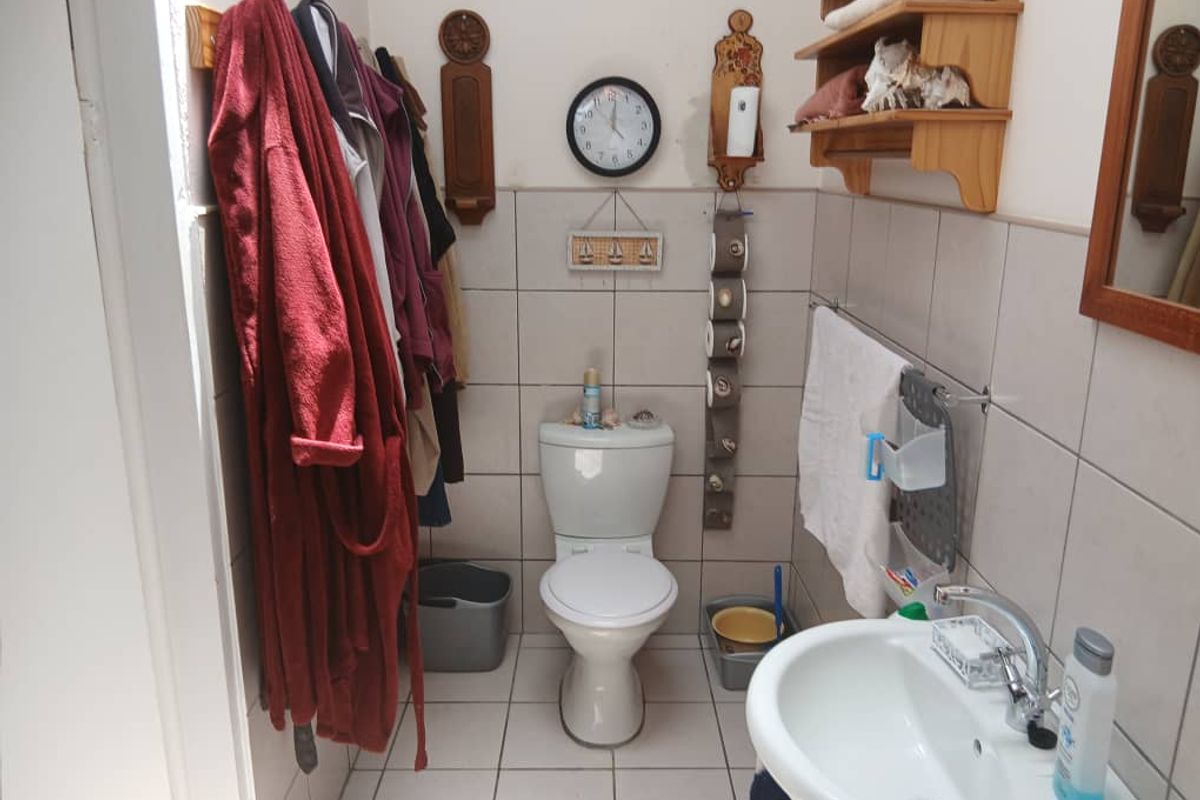 A functional bathroom featuring a standard toilet, wall-mounted basin, and tiled walls, providing essential amenities within the retirement village unit.