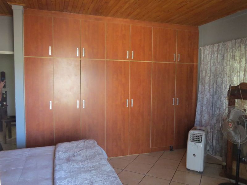 Bedroom featuring extensive floor-to-ceiling built-in wooden cabinetry, tiled flooring, and a timber-clad ceiling.