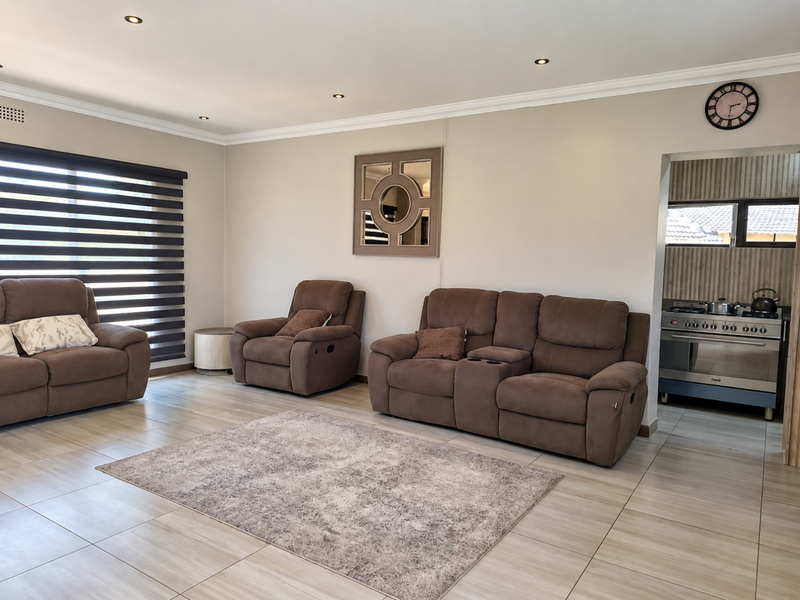 Spacious open-plan living area featuring neutral tiled flooring, recessed lighting, and seamless flow into the adjacent kitchen space.