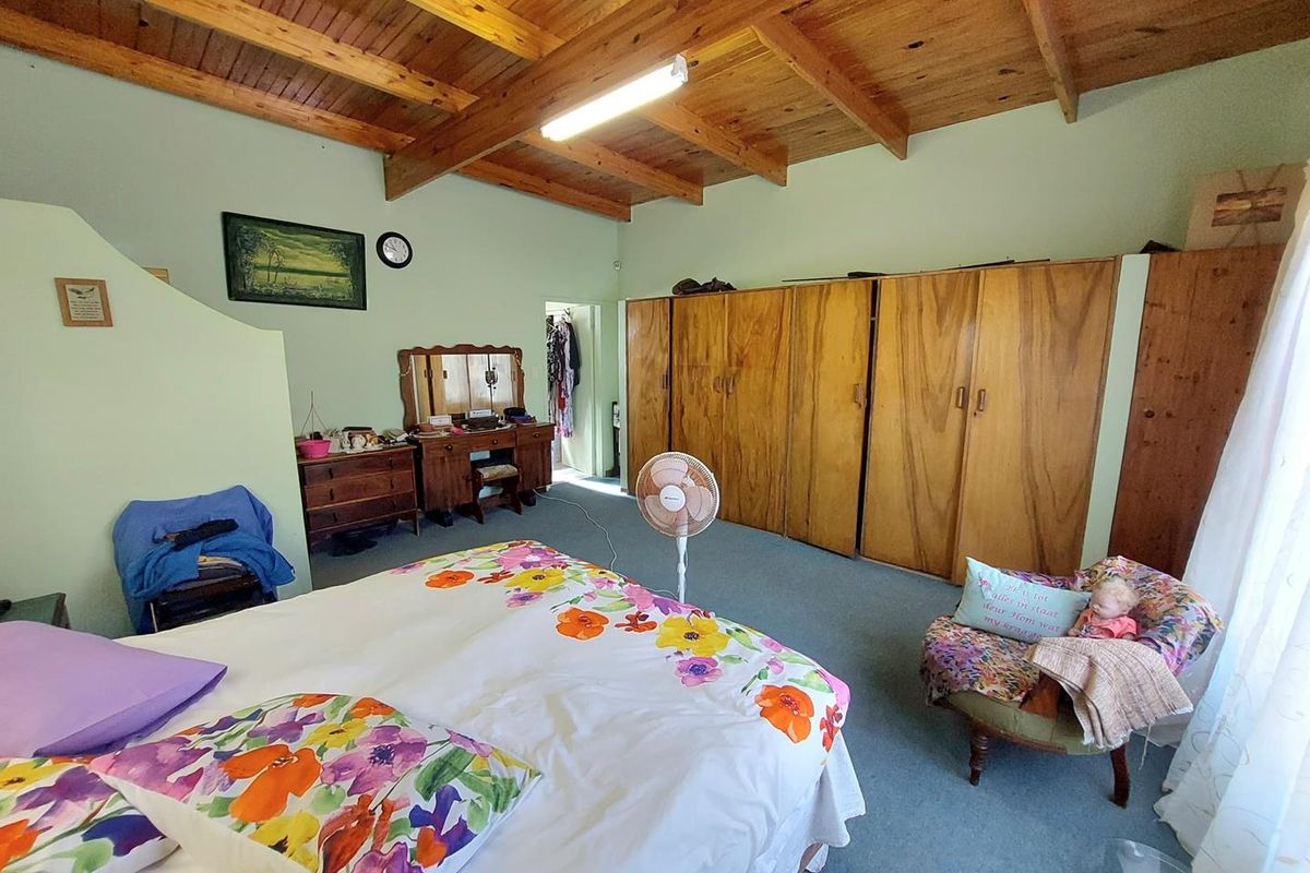 Spacious bedroom featuring exposed timber beam ceiling, built-in wooden cabinetry, and carpeted flooring.