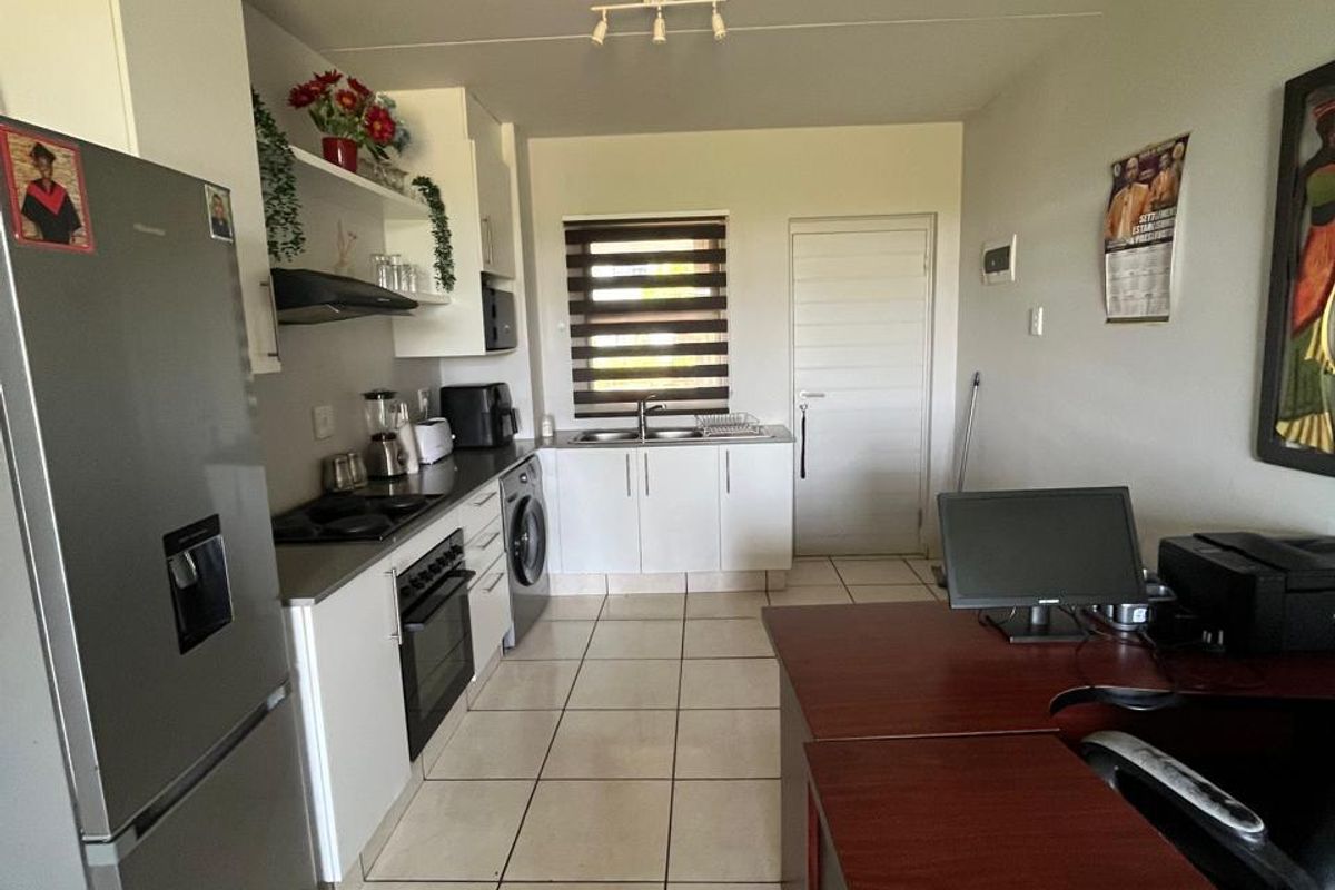 A functional kitchen featuring white cabinetry, tiled flooring, built-in oven and hob, and a stainless steel sink with a window view.