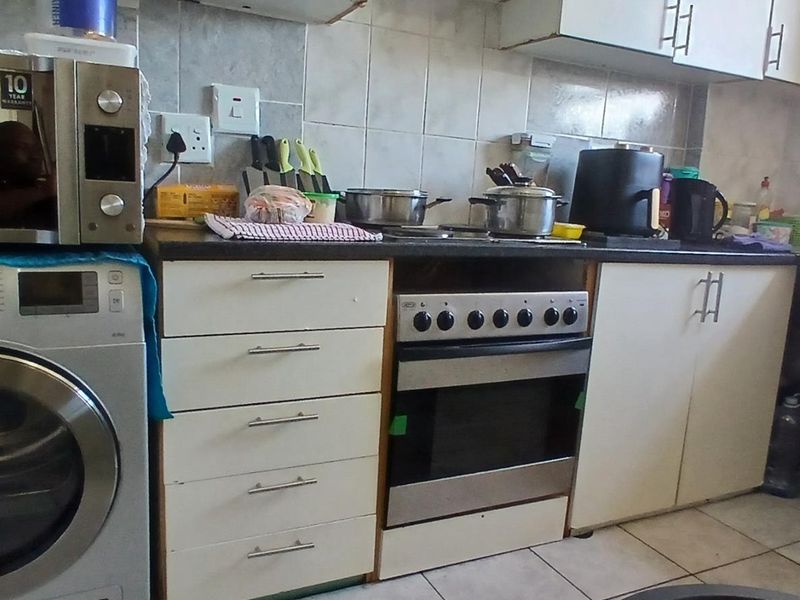 A functional kitchen featuring built-in cabinetry, a stainless steel oven, tiled backsplash, and a sink, offering a practical layout for daily meal preparation.