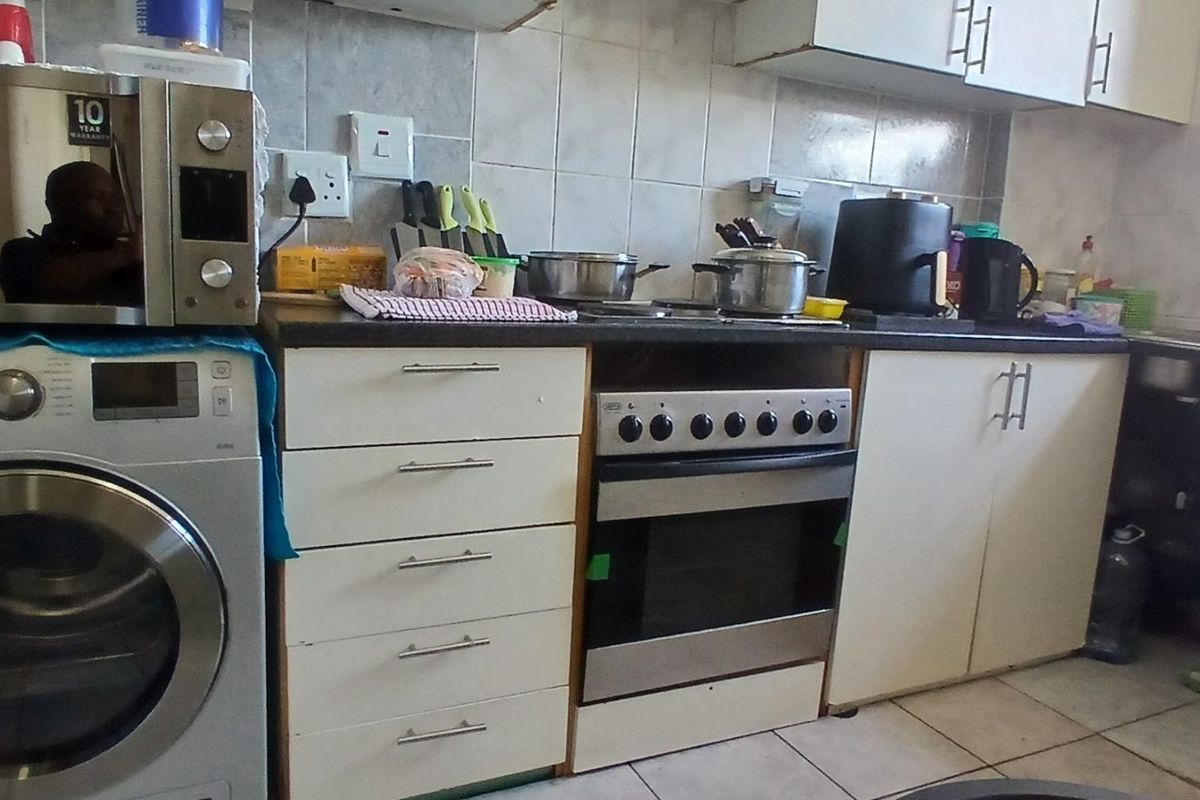 A functional kitchen featuring built-in cabinetry, a stainless steel oven, tiled backsplash, and a sink, offering a practical layout for daily meal preparation.