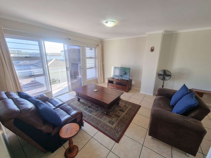A bright living room featuring tiled flooring and large sliding glass doors that provide access to an outdoor balcony area.