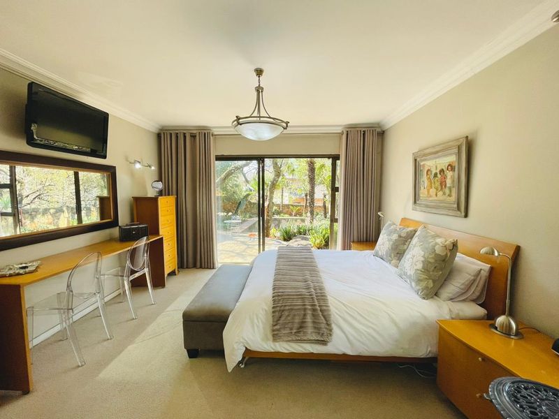 Spacious bedroom featuring neutral carpeting, crown molding, a built-in desk, and sliding glass doors providing direct access to the garden.