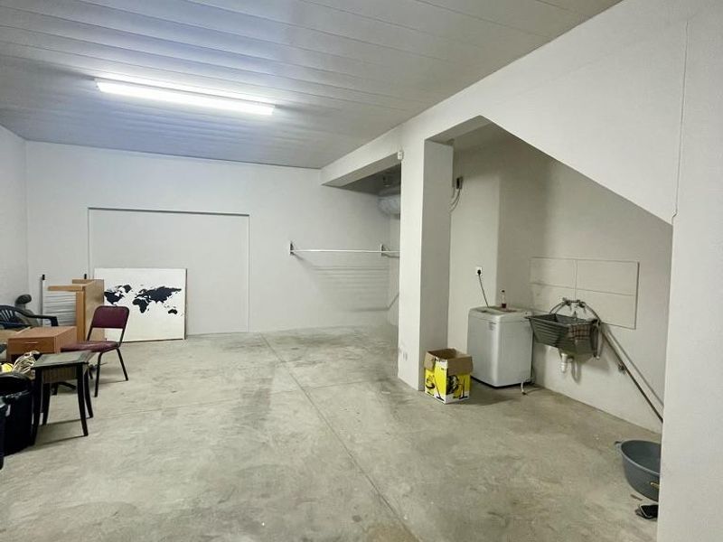 A functional laundry area featuring a utility sink, plumbing connections, and durable concrete flooring in a spacious, open utility room.