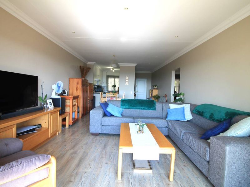 Spacious open-plan living area featuring modern laminate flooring, recessed lighting, and neutral wall tones, seamlessly connecting to the kitchen space.
