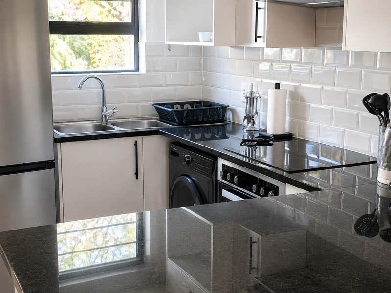 Modern kitchen featuring granite countertops, subway tile backsplash, built-in oven, electric hob, and integrated washing machine with ample cabinetry.
