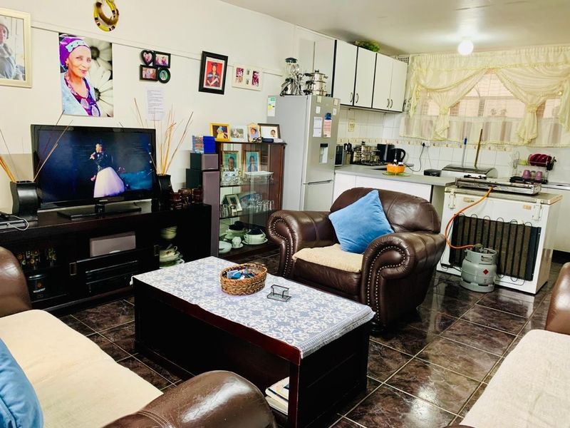 Open-plan living area featuring a combined kitchen space with built-in cabinetry and tiled flooring throughout.