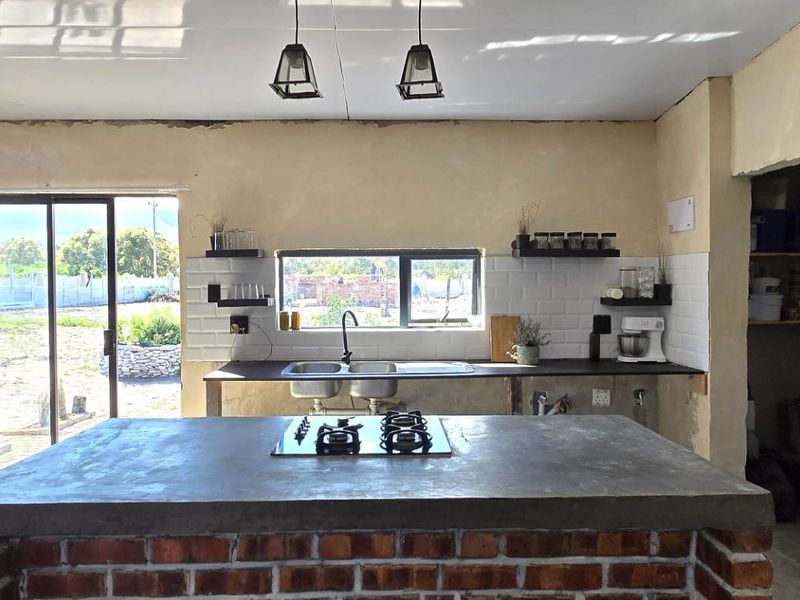 Kitchen featuring a brick-based island with concrete countertop, built-in gas hob, subway tile backsplash, and direct access to the rear garden.