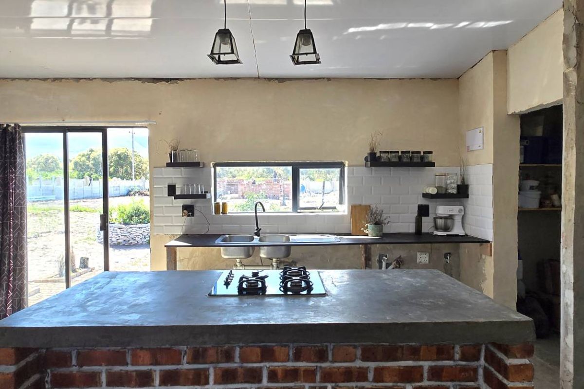 Kitchen featuring a brick-based island with concrete countertop, built-in gas hob, subway tile backsplash, and direct access to the rear garden.