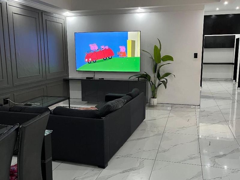 Modern living room featuring elegant wainscoting, polished marble-look floor tiles, and recessed ceiling lighting, creating a clean and contemporary aesthetic.